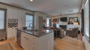 A spacious kitchen with white cabinetry, a large island, and a dining area with a fireplace. - On 30A, 4 Houses from Beach with Beachfront Pool, between Rosemary and Alys (Seacrest Beach)