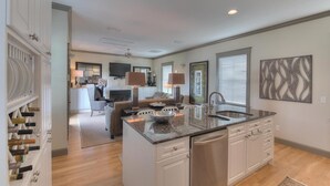 A modern kitchen with a central island, white cabinetry, and a built-in dishwasher. - On 30A, 4 Houses from Beach with Beachfront Pool, between Rosemary and Alys (Seacrest Beach)