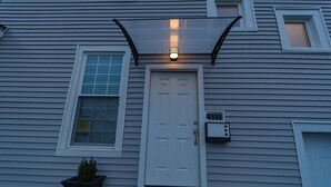 A house with a white door, a small window, and a porch light. - Newly 5 Star Rental (New York)