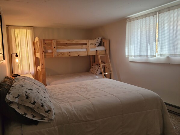 A bunk bed room with a ladder, a bedside table with a lamp, and a window with curtains. - On Mountain Ski House!! (Carrabassett Valley)