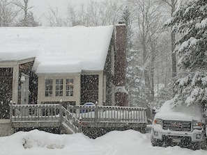 A snow-covered house with a porch and a staircase leading to the entrance. - On Mountain Ski House!! (Carrabassett Valley)