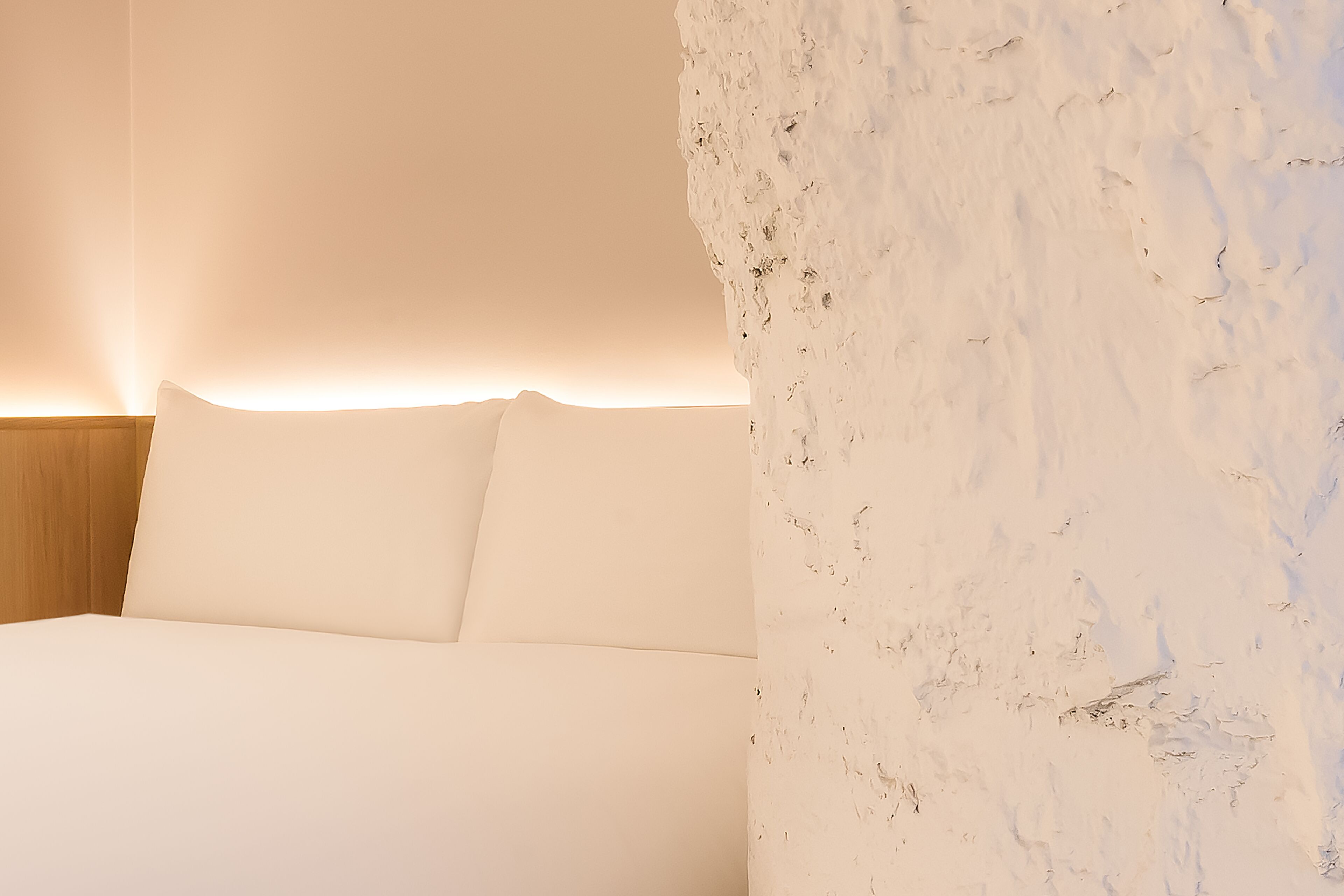 A bedroom with a bed, white walls, and a wooden headboard.