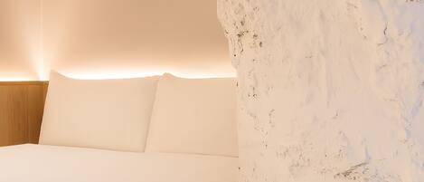 A bedroom with a bed, white walls, and a wooden headboard.