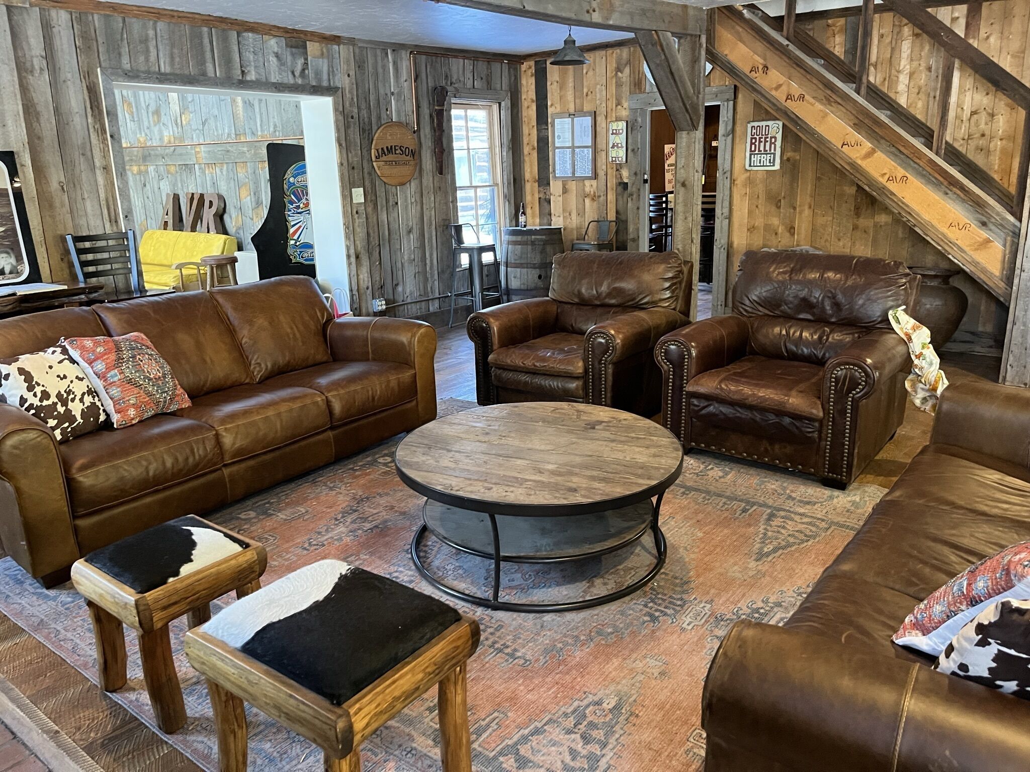 A rustic interior with leather furniture, a wooden coffee table, and a staircase.