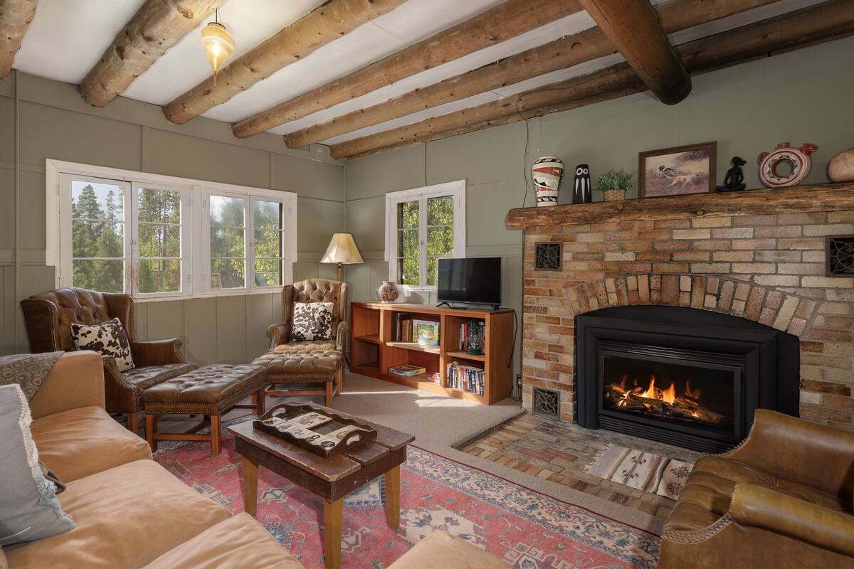 A cozy living room with leather sofas, a fireplace, a television, and a bookshelf.
