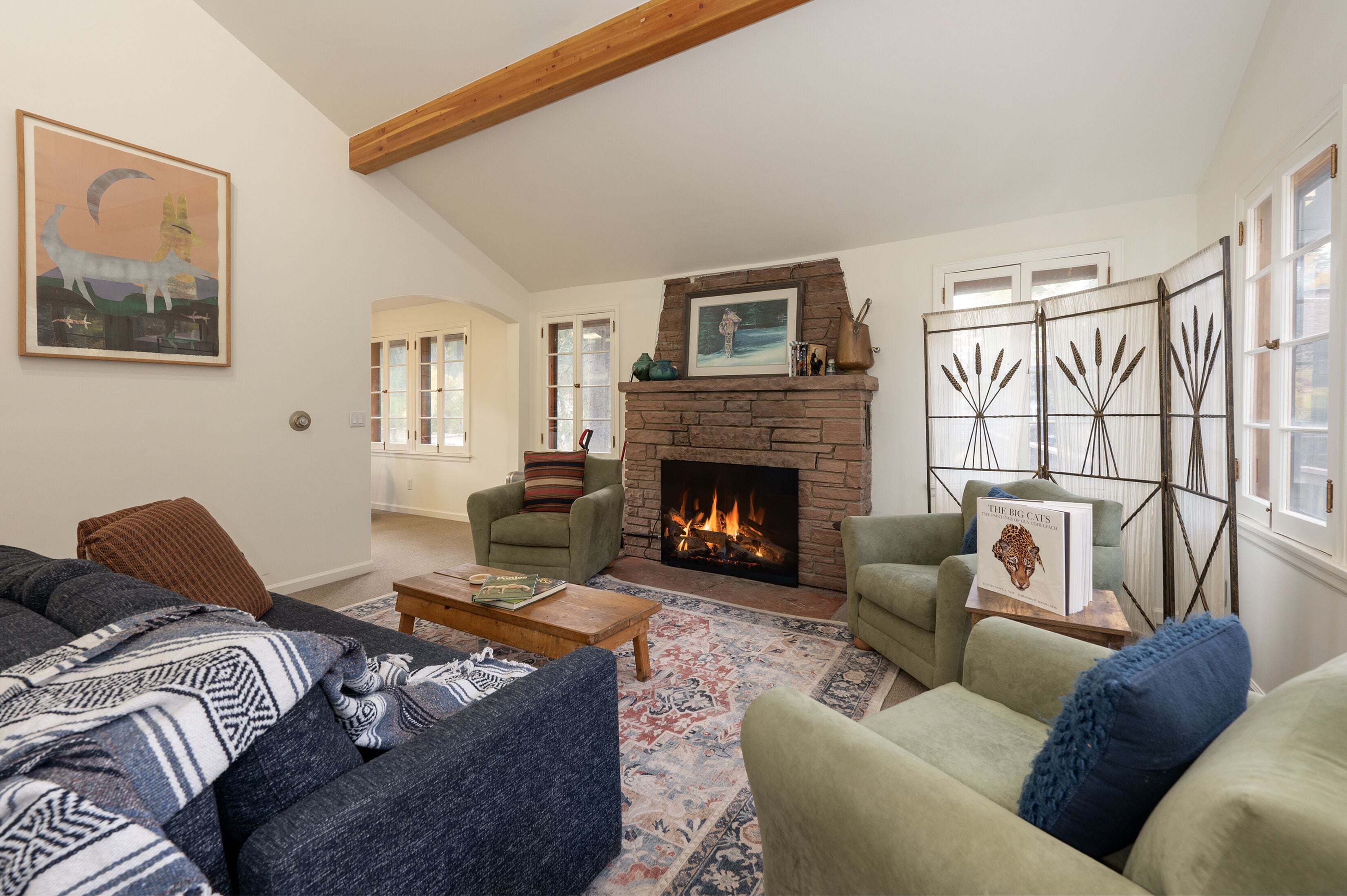 A cozy living room with a fireplace, comfortable seating, and a large window.