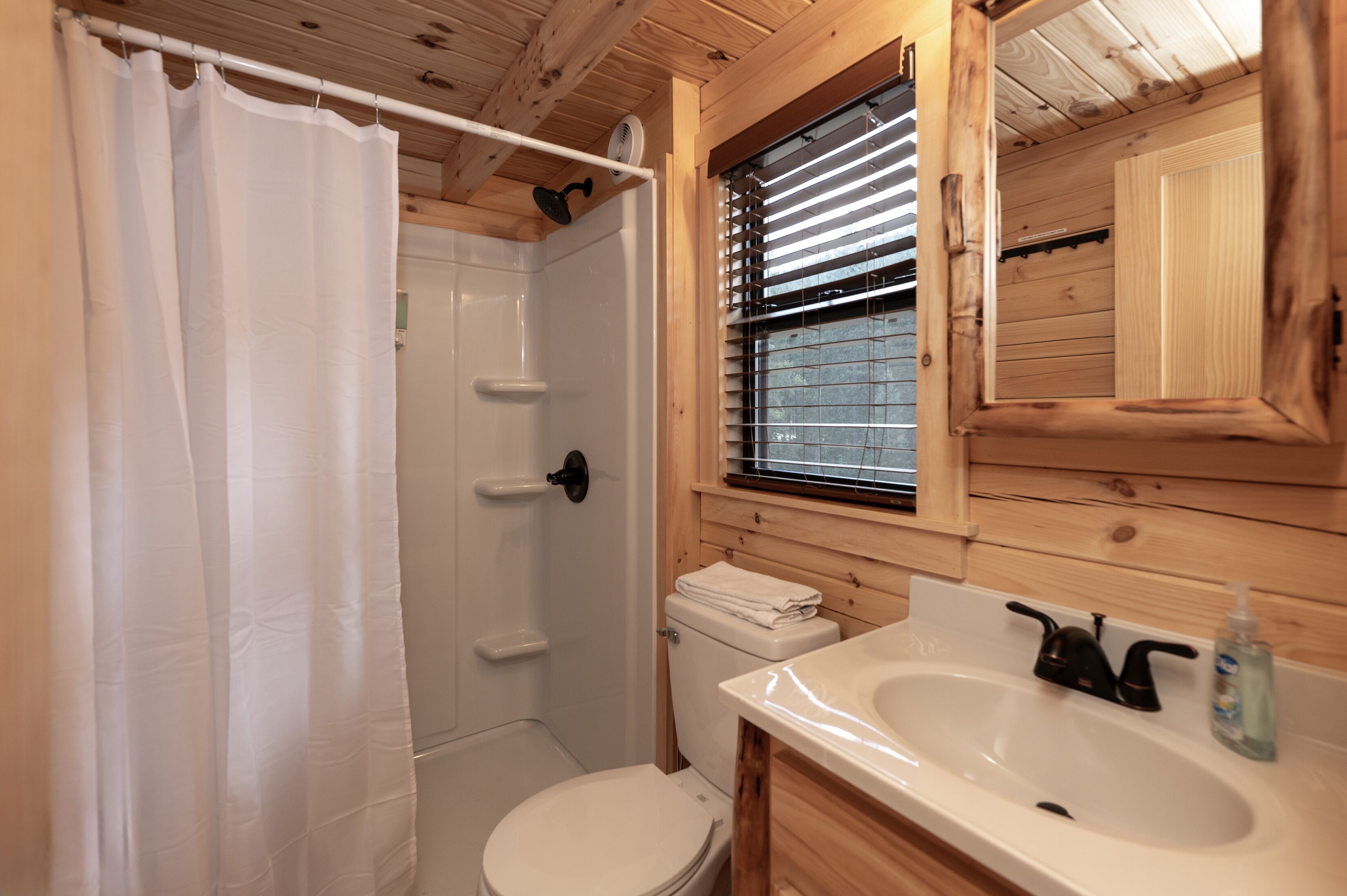 Een badkamer met een douche, toilet, wastafel en houten lambrisering.
