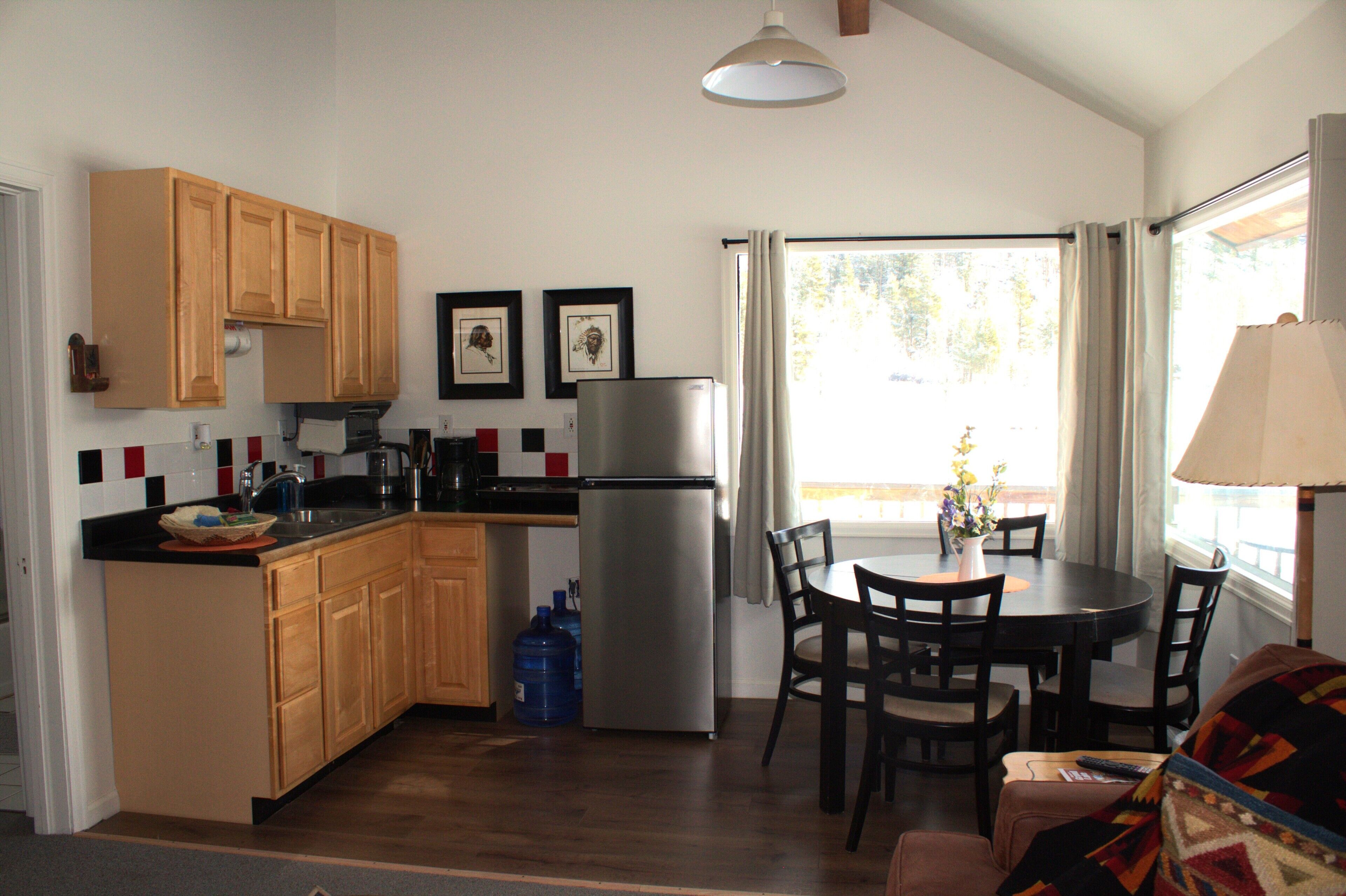 Una cocina compacta con armarios de madera, un refrigerador y una zona de comedor con mesa y sillas.