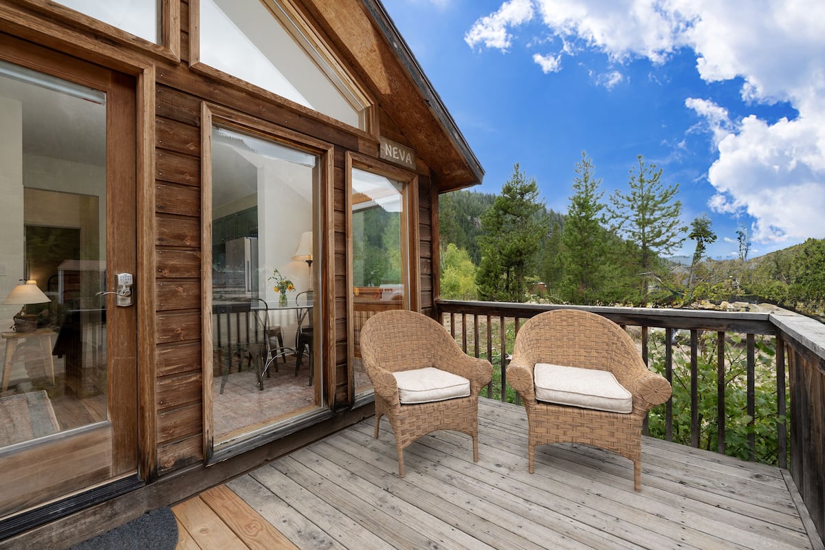A wooden deck with wicker chairs and a glass door leading to a room.