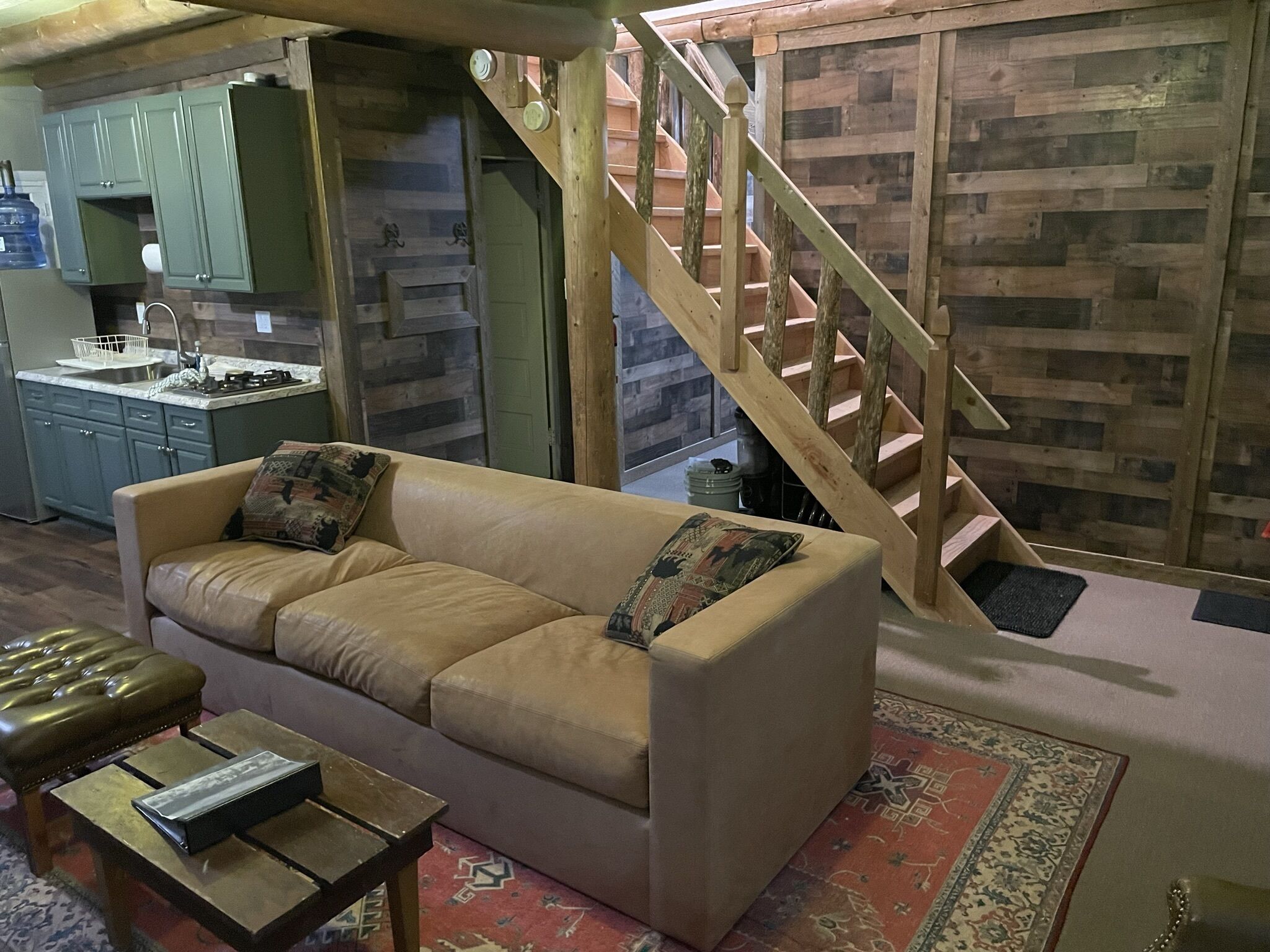 A cozy living room with a sofa, a coffee table, and a wooden staircase.