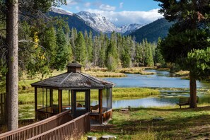 A wooden gazebo with a glass enclosure overlooking a lake, surrounded by trees and mountains. - Arapaho Valley Ranch (Granby)