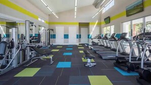 Un gimnasio con cintas de correr, máquinas de pesas y colchonetas de ejercicio.
