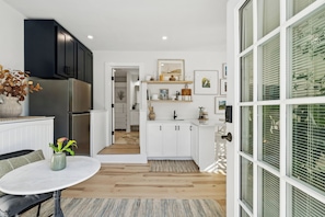 A modern kitchen with white cabinets, a stainless steel refrigerator, and a dining area with a round table.