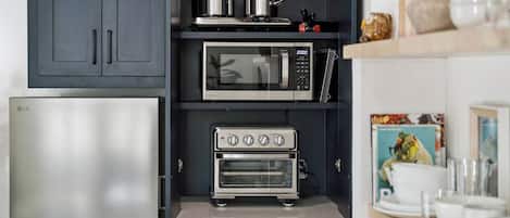A modern kitchen with a built-in microwave, toaster oven, and a stainless steel refrigerator.