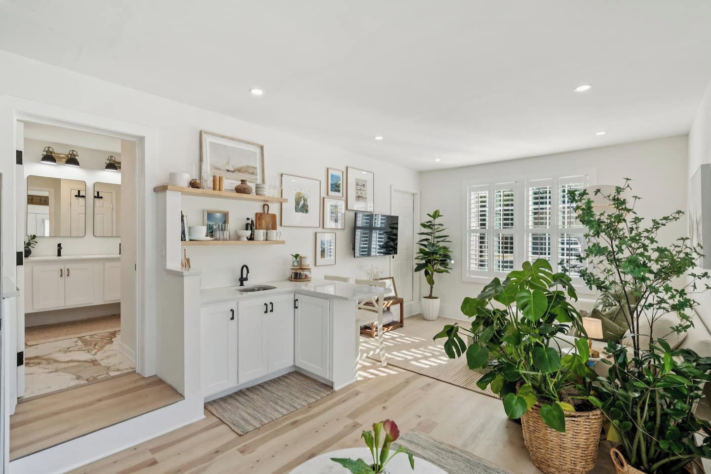 A modern kitchen with white cabinets, a built-in oven, and a dining area with a table and chairs.