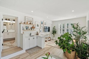A modern kitchen with white cabinets, a built-in oven, and a dining area with a table and chairs.