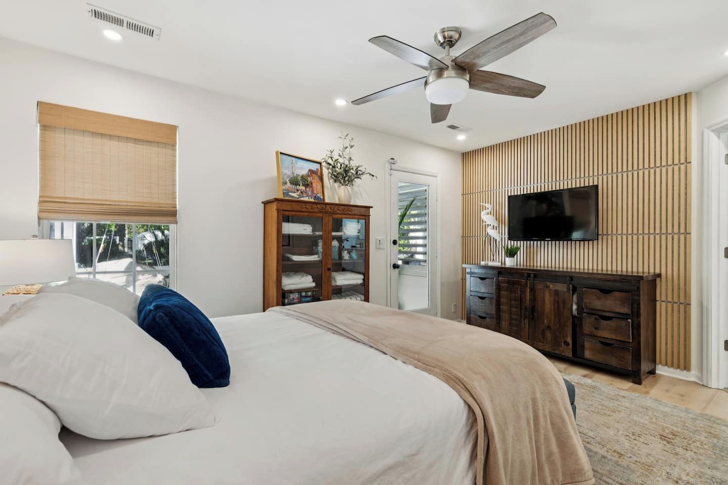 Ein Schlafzimmer mit Bett, Kleiderschrank, Fernseher und Deckenventilator.