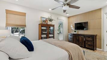Ein Schlafzimmer mit Bett, Kleiderschrank, Fernseher und Deckenventilator.