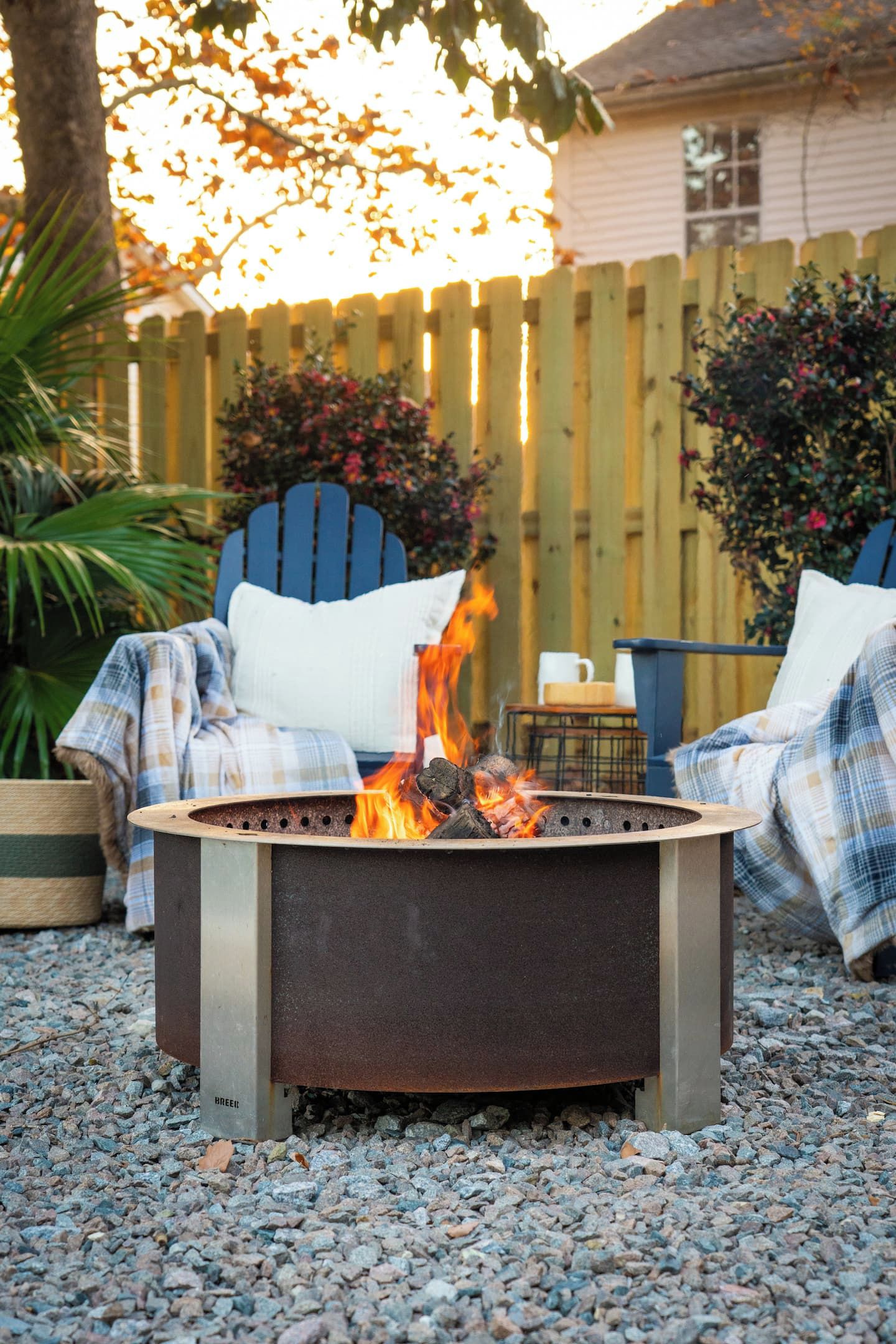 A fire pit with a metal frame and a flat top, surrounded by gravel.