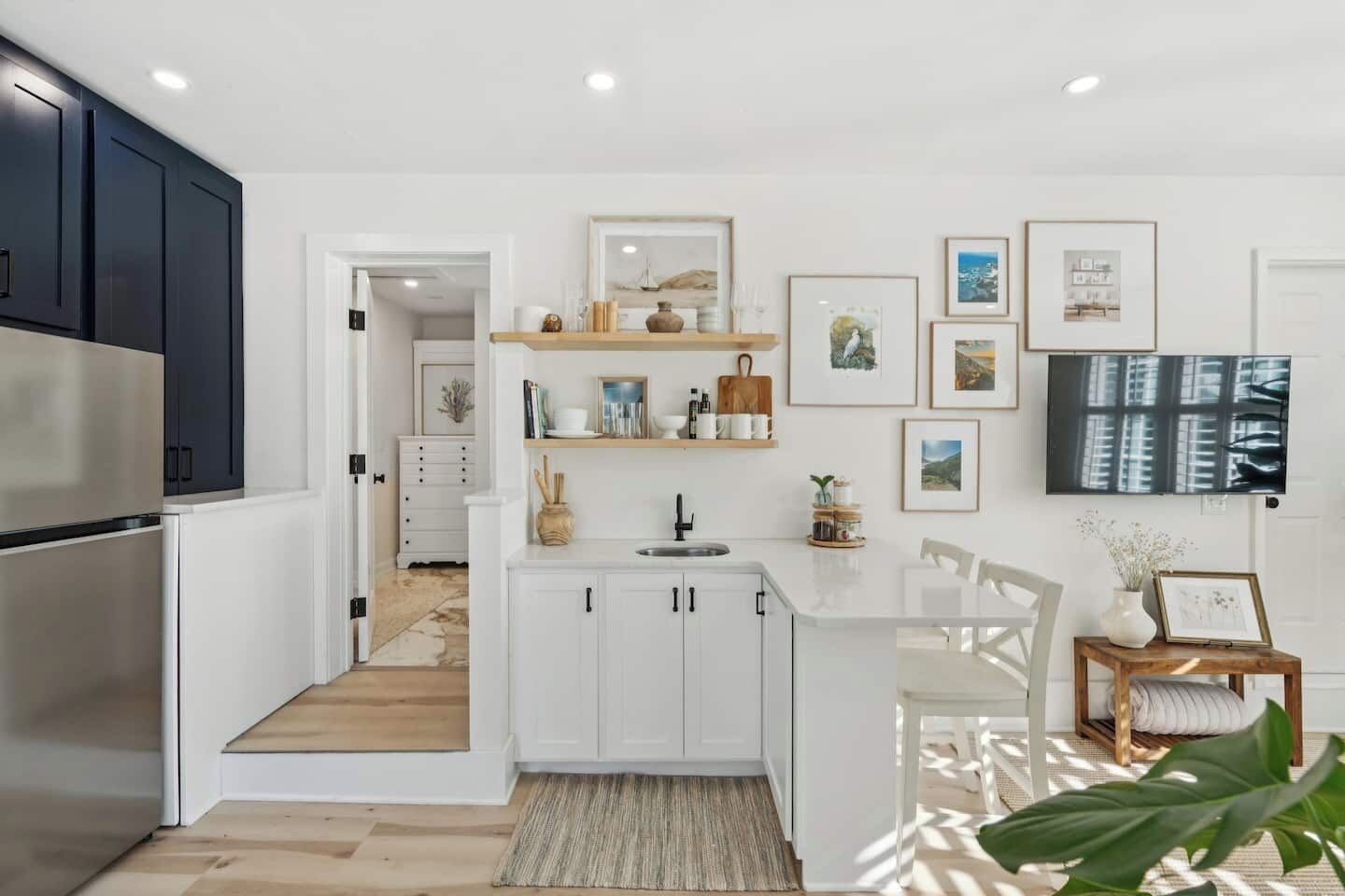 A modern kitchen with white cabinetry, a built-in island, and a large flat-screen TV.
