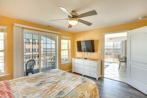 Ein Schlafzimmer mit Bett, Kommode, Deckenventilator und Fernseher.