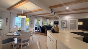 A modern kitchen with a central island, white cabinetry, and wooden beams on the ceiling. - Peaceful ocean front cottage. (Summerland Key)