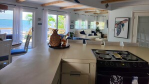 A spacious living area with a kitchen, a dining area, and a view of the ocean. - Peaceful ocean front cottage. (Summerland Key)