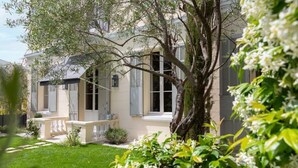 A two-story house with a well-maintained garden and a large tree in the front yard.