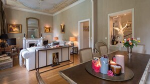 A spacious living room with a fireplace, dining area with candles, and a staircase leading to another level.