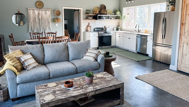 Une cuisine moderne avec des meubles blancs, un réfrigérateur en acier inoxydable et un coin repas comprenant une table et des chaises en bois.