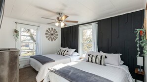 Un dormitorio con dos camas, un ventilador de techo y un adorno en la pared.