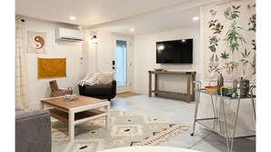 A modern living room with a sofa, coffee table, and a TV mounted on the wall. - Luxury Sea Cabin Guest Suite - Across from Beach (Folly Beach)