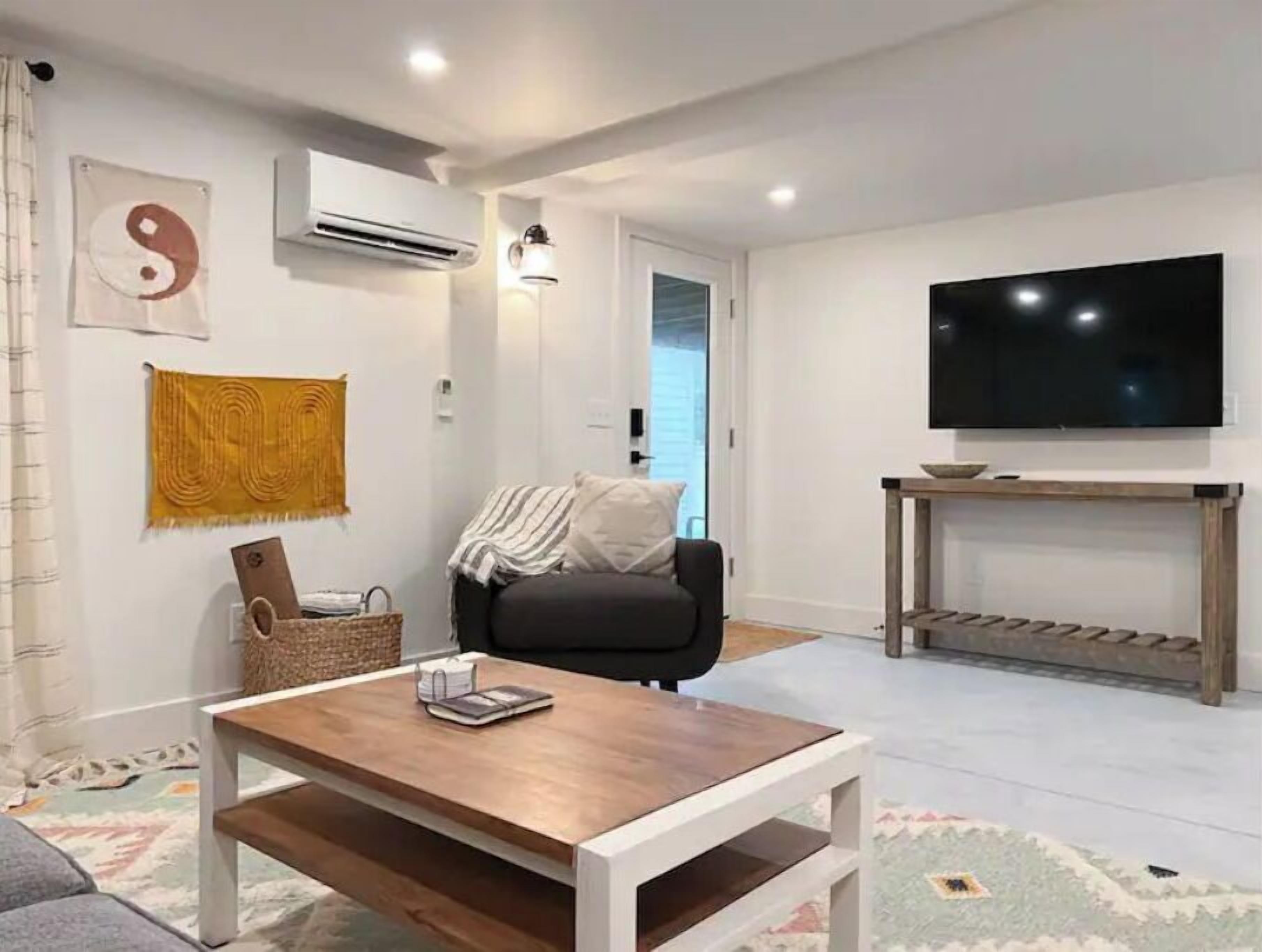 A modern living room with a sofa, a coffee table, a TV, and a wall-mounted air conditioner.