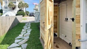 A wooden shed with a stone pathway leading to it, a white garage door, and a wooden fence. - Luxury Sea Cabin Guest Suite - Across from Beach (Folly Beach)
