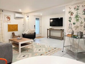 A modern living room with a sofa, coffee table, and a TV mounted on the wall.