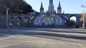 A historic church with a prominent spire, an arched entrance, and a large open plaza in front.