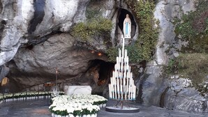 A rock formation with a statue and a candle arrangement.