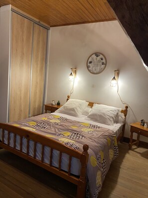 A bedroom with a wooden bed, two bedside lamps, a wall clock, and a wooden wardrobe.