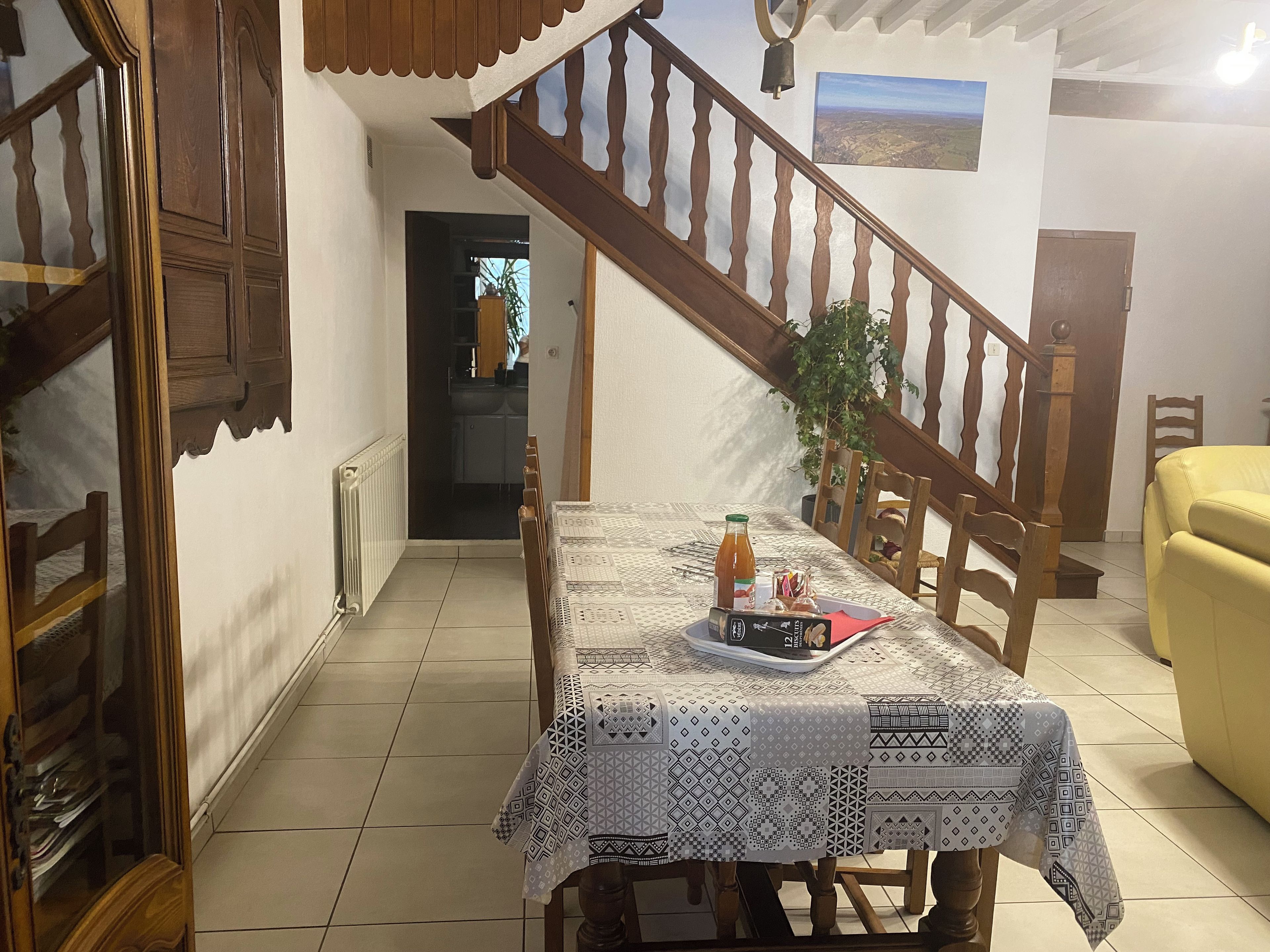 A dining area with a table set for two, a staircase, and a view of the outdoors.