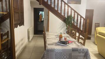 Un coin repas avec une table dressée pour deux personnes, un escalier et une vue sur l’extérieur.