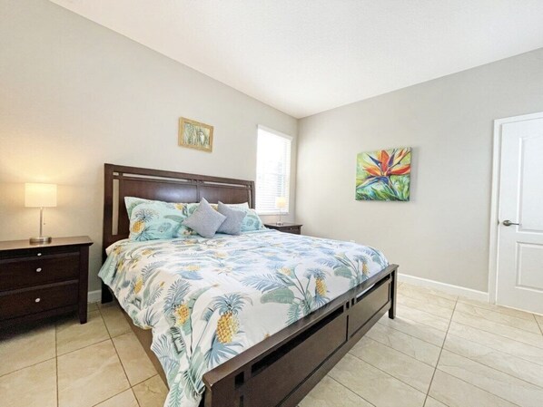 A bedroom with a bed, nightstands, a lamp, and artwork on the walls.