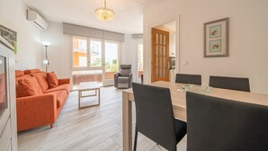 Un salon moderne avec un canapé, une table à manger et des chaises. On y trouve un lustre, une cheminée et une vue sur l’extérieur.