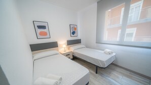 Une chambre d’hôtel avec deux lits, une table de chevet avec une lampe et des œuvres d’art accrochées au mur.