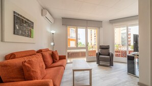 Un salon moderne avec un canapé, une table et une chaise. Il y a un balcon avec une balustrade et une vue sur les immebles.