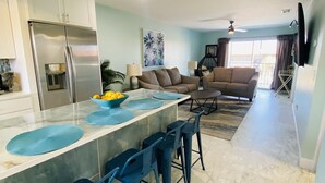 Una cocina moderna con una isla grande, taburetes de bar y una zona de comedor con un sofá.