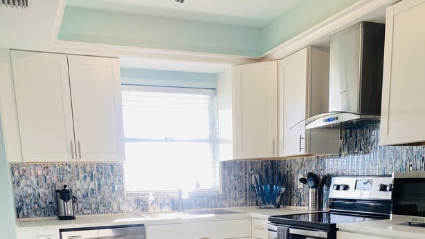 Una cocina moderna con una isla central, electrodomésticos de acero inoxidable y un salpicadero decorativo.