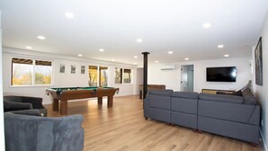 A spacious living room with a pool table, a gray sofa, and a flat-screen TV mounted on the wall. - Kid and Dog Friendly Home w/ Amazing Views! (Glenwood Springs)