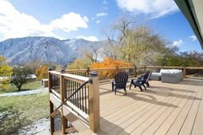 A deck with outdoor seating and a view of mountains.