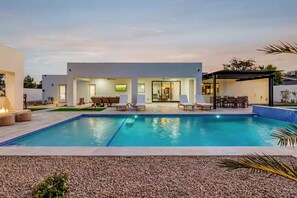 A modern outdoor pool area with a rectangular pool, lounge chairs, and a covered seating area. - Querencia  | Pool, Hot Tub, Putting Green, Fire Pit, TPC Golf | Scottsdale (Scottsdale)