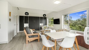 Un intérieur moderne comprenant un canapé, une table à manger, des chaises et un téléviseur.